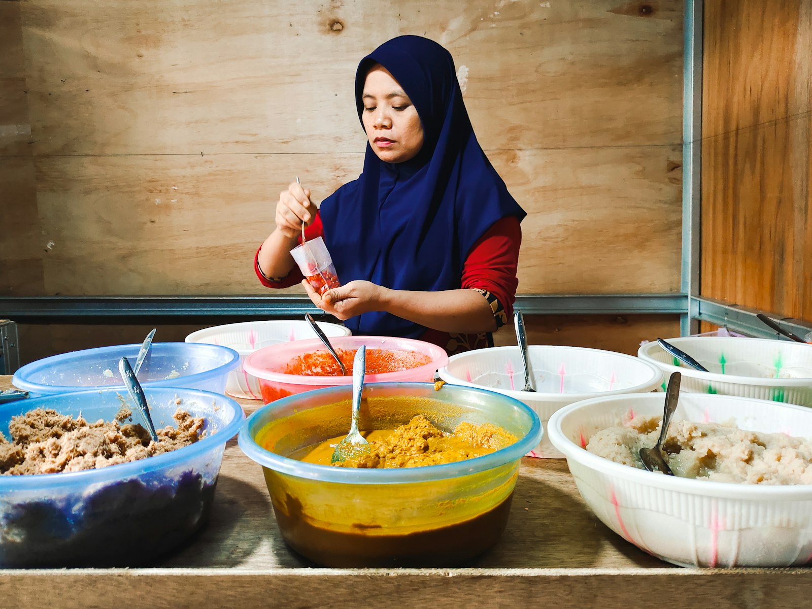 Ibu penjual menyiapkan aneka lauk di warung